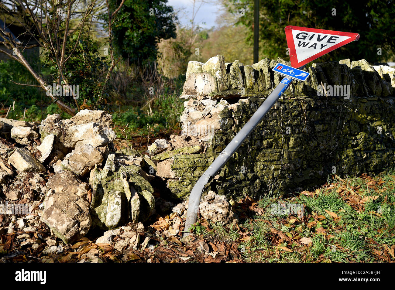 Give Way sign and wall that has been knocked down, England Stock Photo