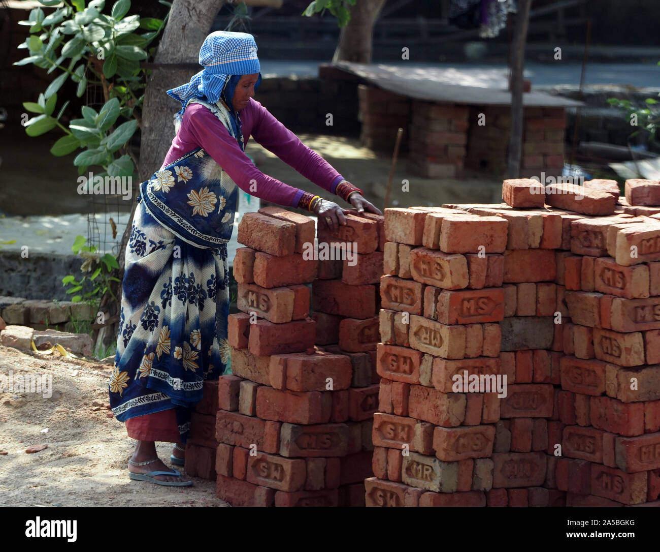 A woman loading and carrying bricks on a building site in Agra, India. Stock Photo