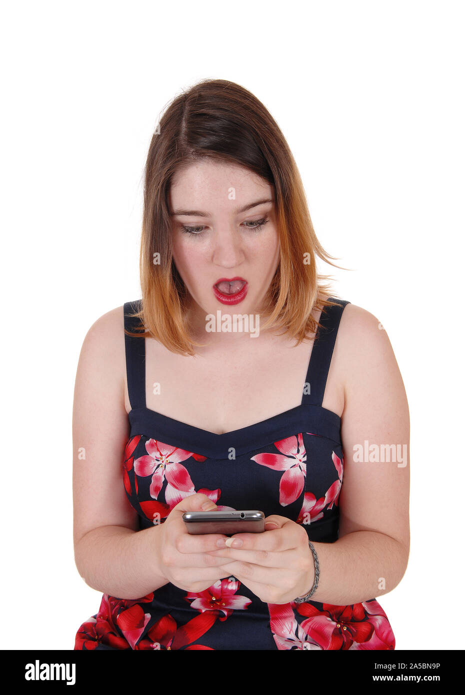 A scary looking young woman holding her cell phone disbelieving what the message says, isolated for white background Stock Photo
