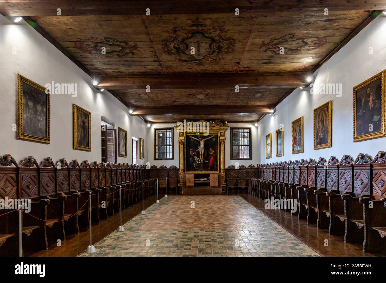 Large room with a painted ceiling and a row of wooden stalls. Convento de Santa Clara (Santa Clara Convent), Funchal, Madeira, Portugal Stock Photo