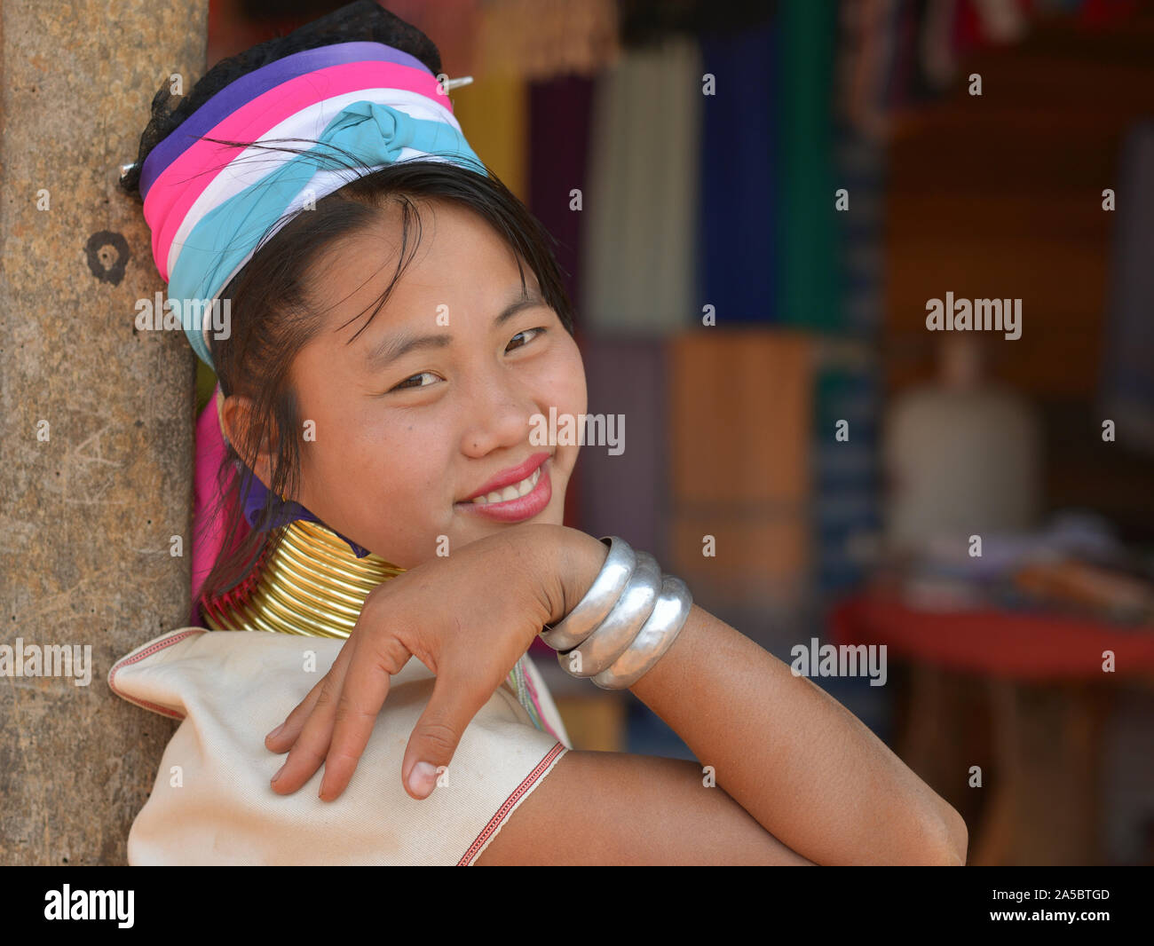 Young beautiful Myanmarese Kayan Lahwi longneck woman (“giraffe woman”) with tribal brass neck rings/coils poses for the camera. Stock Photo