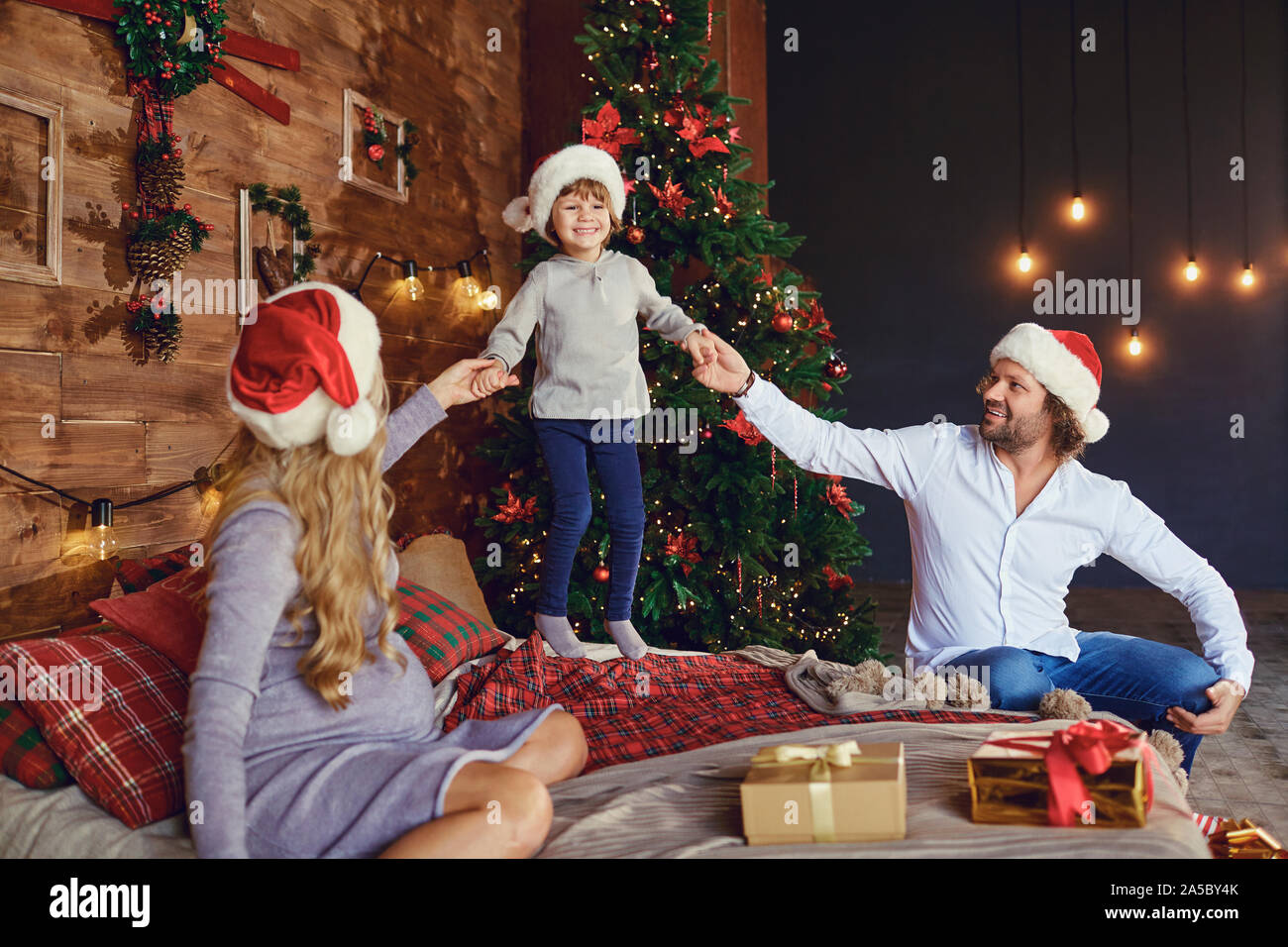 Laughing kid with parents on bed in Xmas time Stock Photo