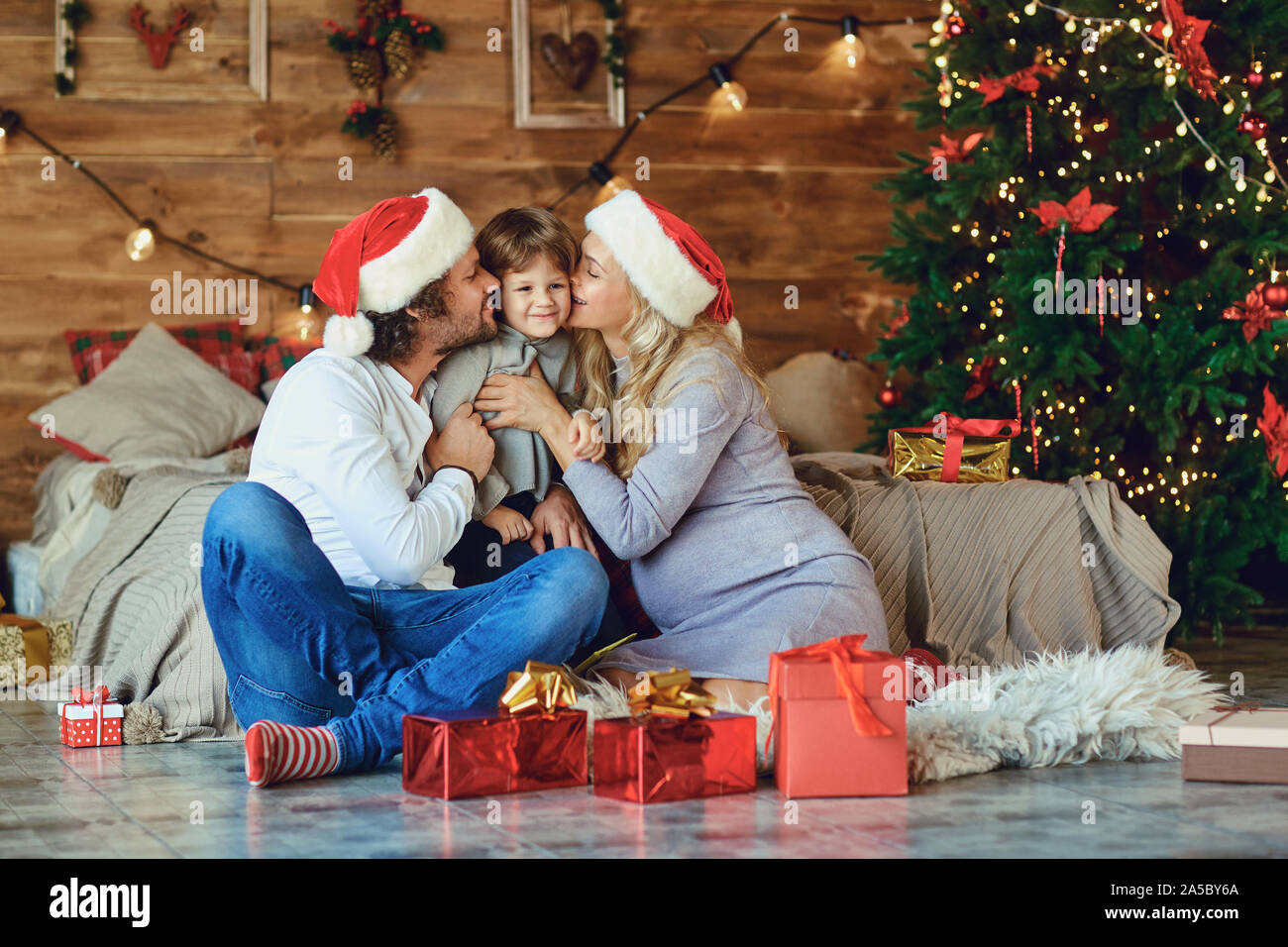 Family kisses the child in the house at Christmas. Stock Photo