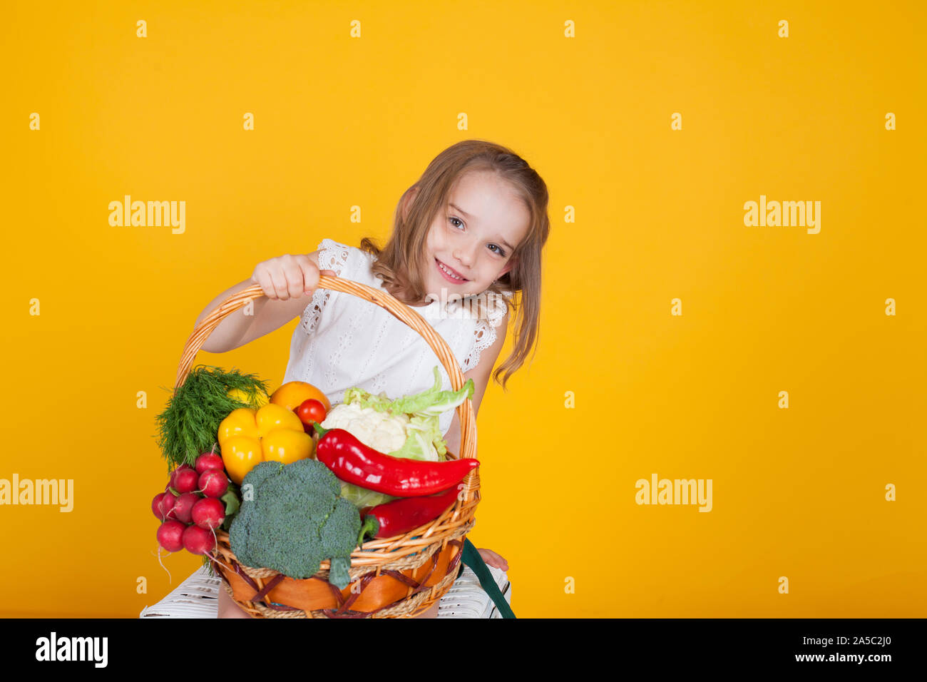 Beautiful little girl holding a basket of ripe vegetables Stock Photo ...