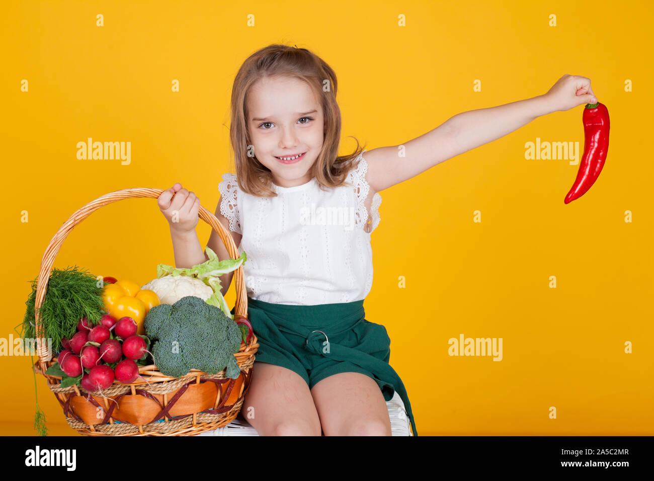 Beautiful little girl holding a basket of ripe vegetables Stock Photo ...