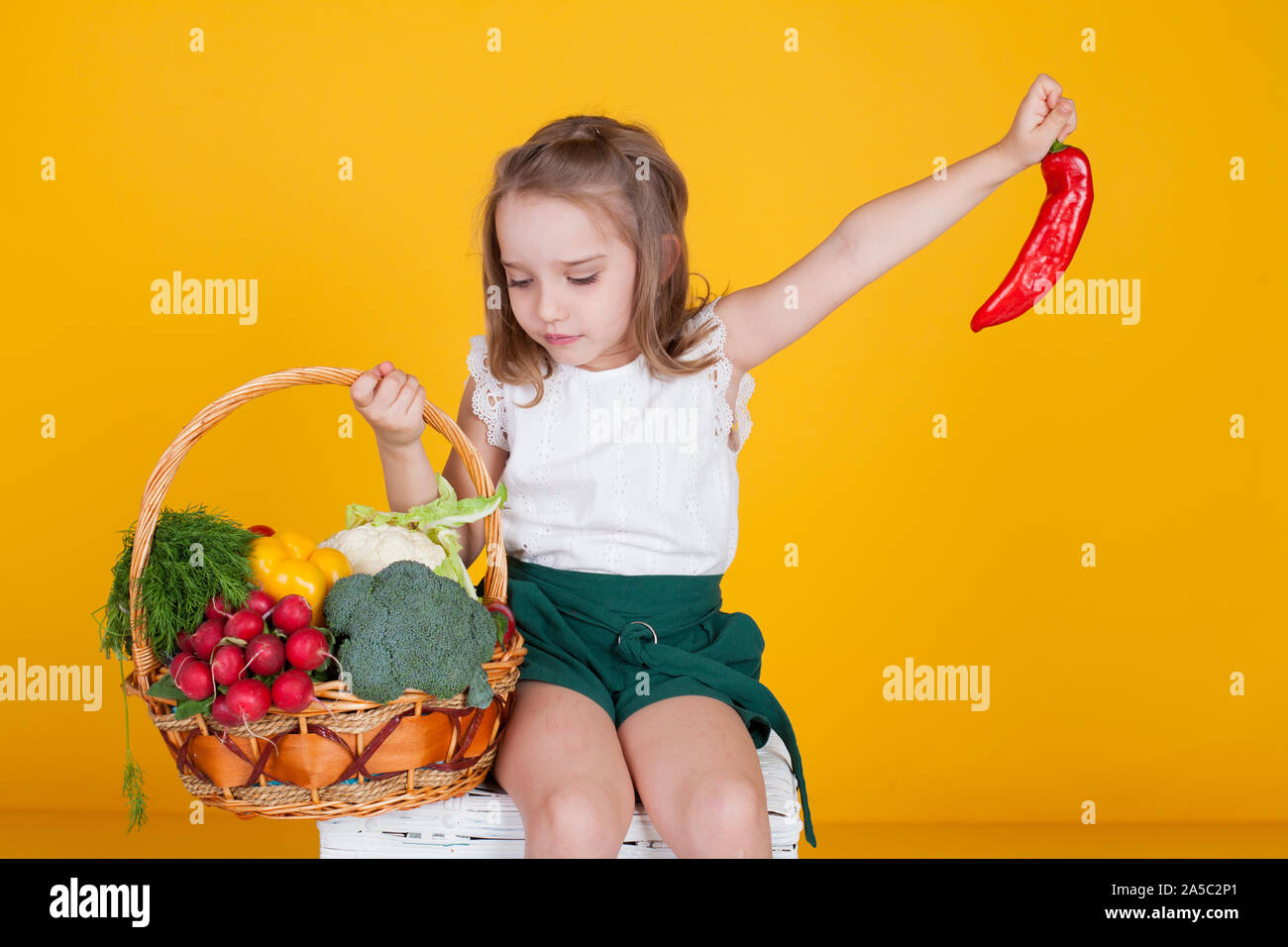 Beautiful little girl holding a basket of ripe vegetables Stock Photo ...