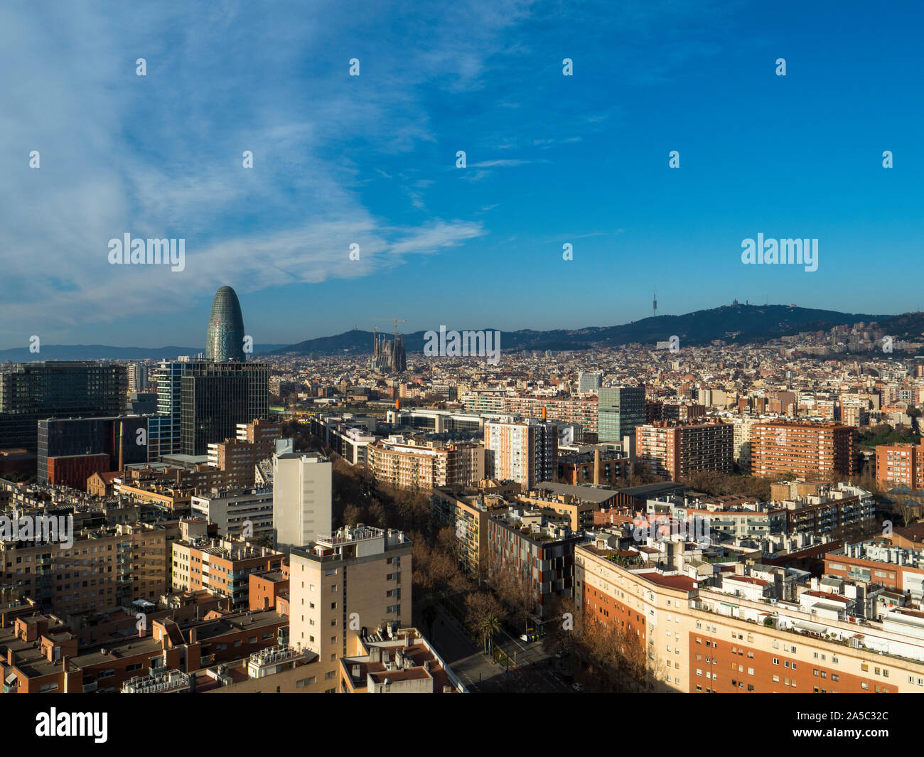 Barcelona cityscape featuring famous landmarks Torre Glories, La Sagrada Familia and the hillside of Tibidabo in the distance - Barcelona, Catalonia, Stock Photo