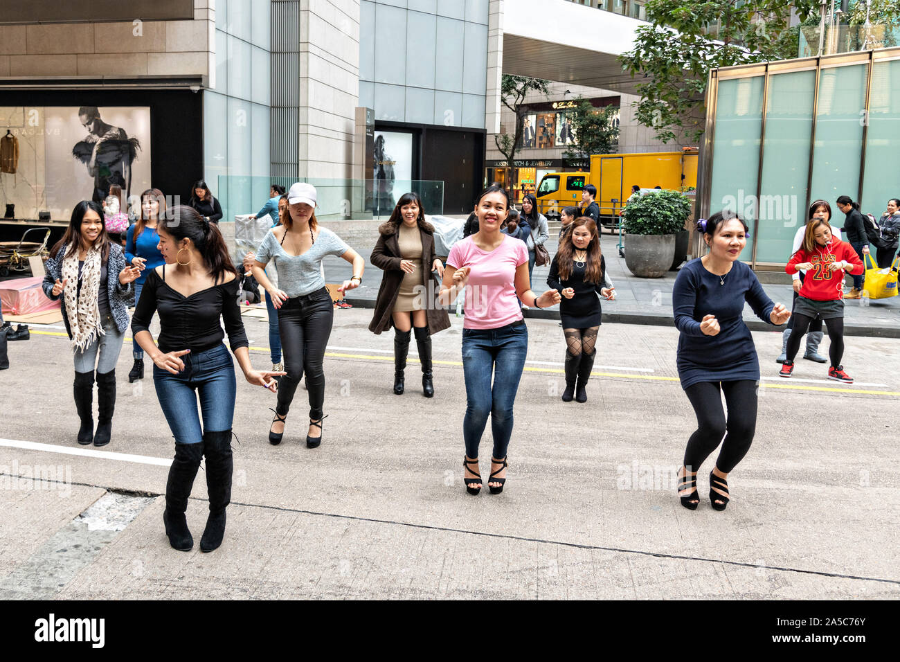 Filipino domestic workers gather on their day-off and hold an impromptu line dance in Central District, Hong Kong. Approximately 130,000 Filipino domestic servants work in Hong Kong and all have Sundays off. Stock Photo