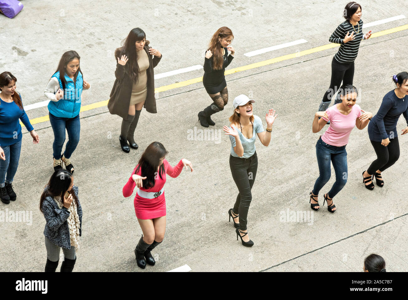 Filipino domestic workers gather on their day-off and hold an impromptu line dance in Central District, Hong Kong. Approximately 130,000 Filipino domestic servants work in Hong Kong and all have Sundays off. Stock Photo