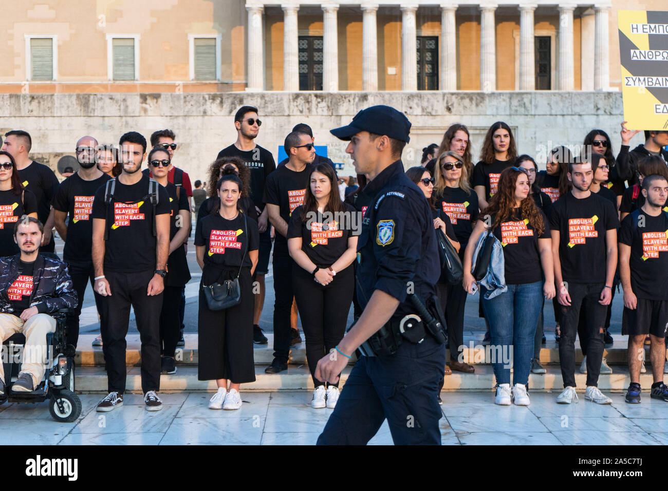 A police officer passes in front of the participants standing at the Greek Parliament during the parade.Walk for Freedom is a global response to human trafficking. It’s an awareness and fundraising event rallying thousands of abolitionists, taking millions of steps in hundreds of cities all over the world. Stock Photo