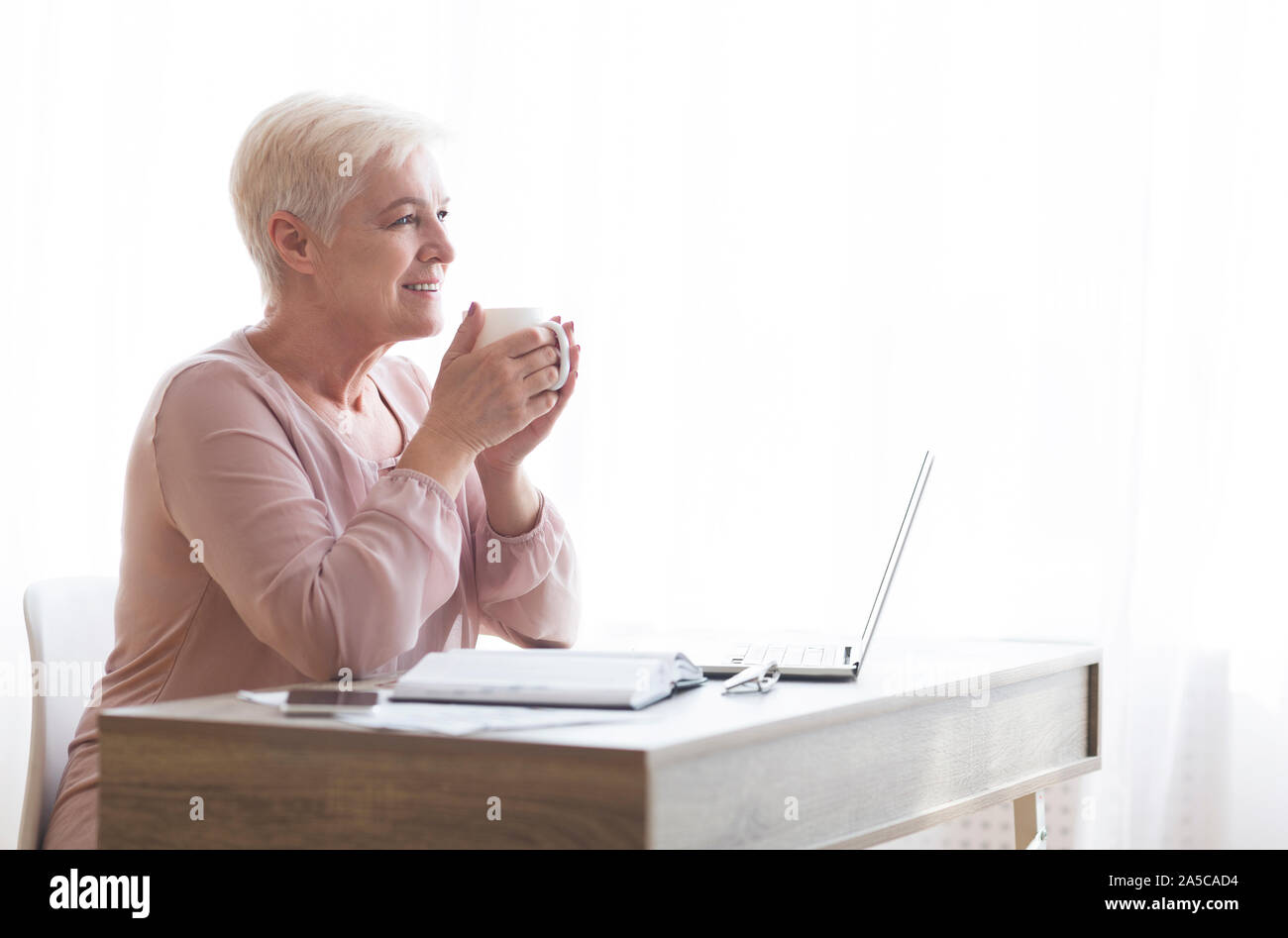 Peaceful old lady having coffee break during working day Stock Photo