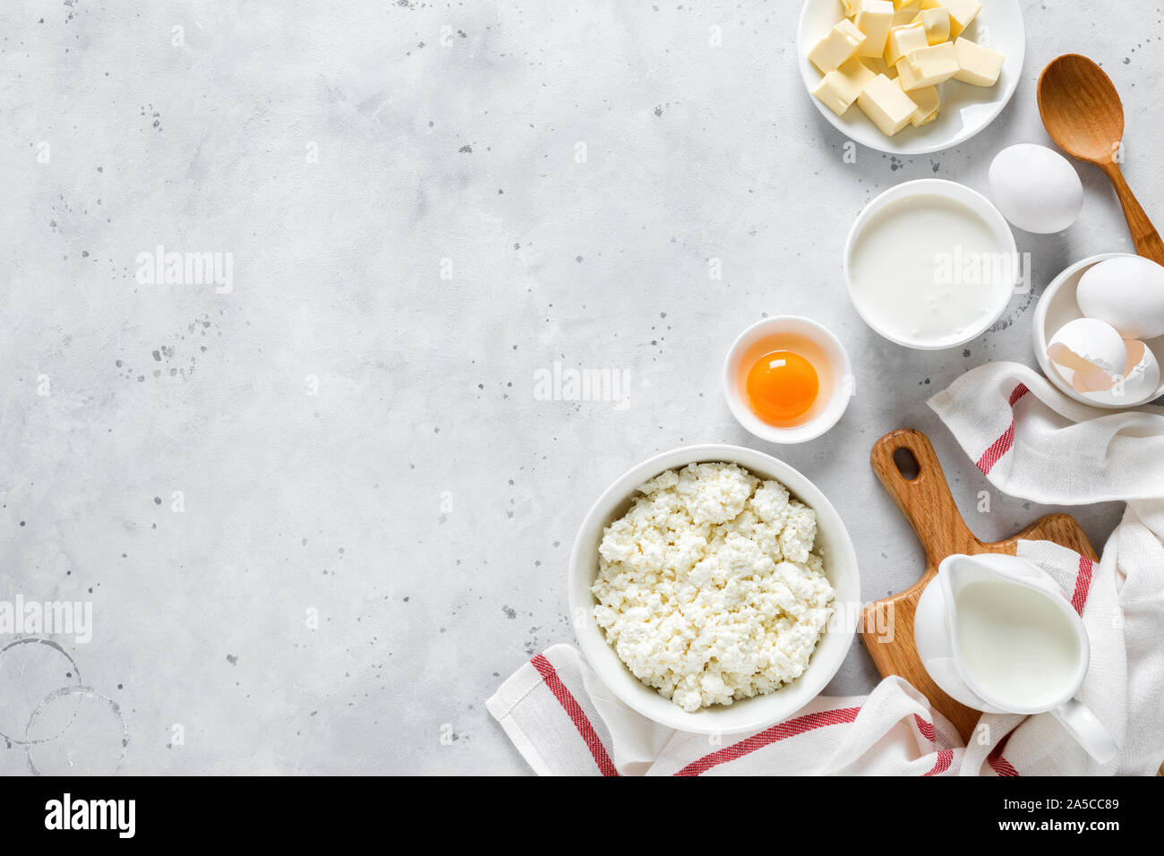 Pitcher with milk, egg, cottage cheese, butter and yogurt on kitchen table. Ingredients for cooking on kitchen table with copy space. Culinary backgro Stock Photo