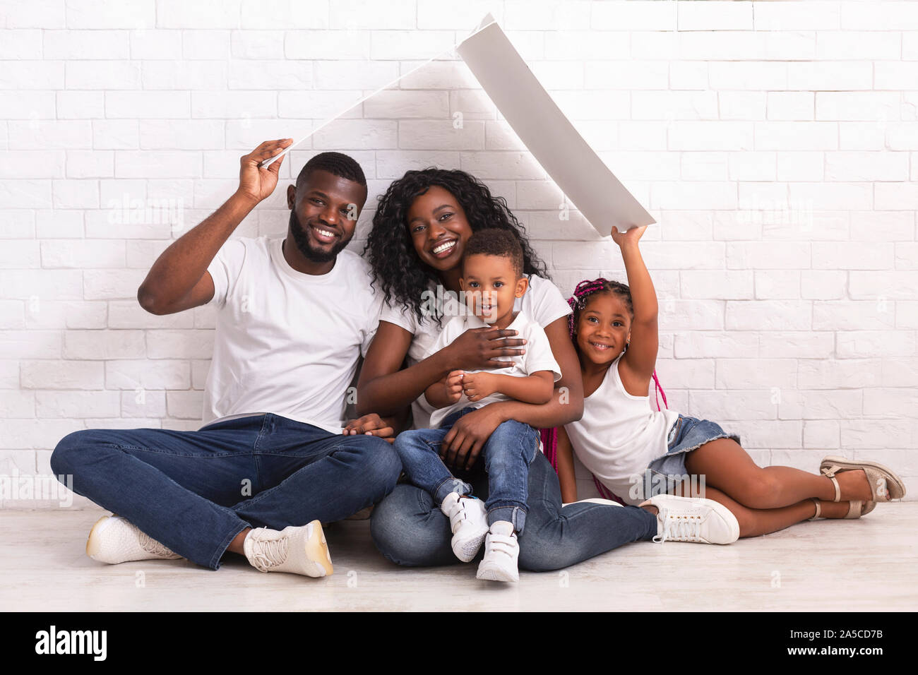 Happy African American Family Sitting On Floor Under Symbolic Roof ...