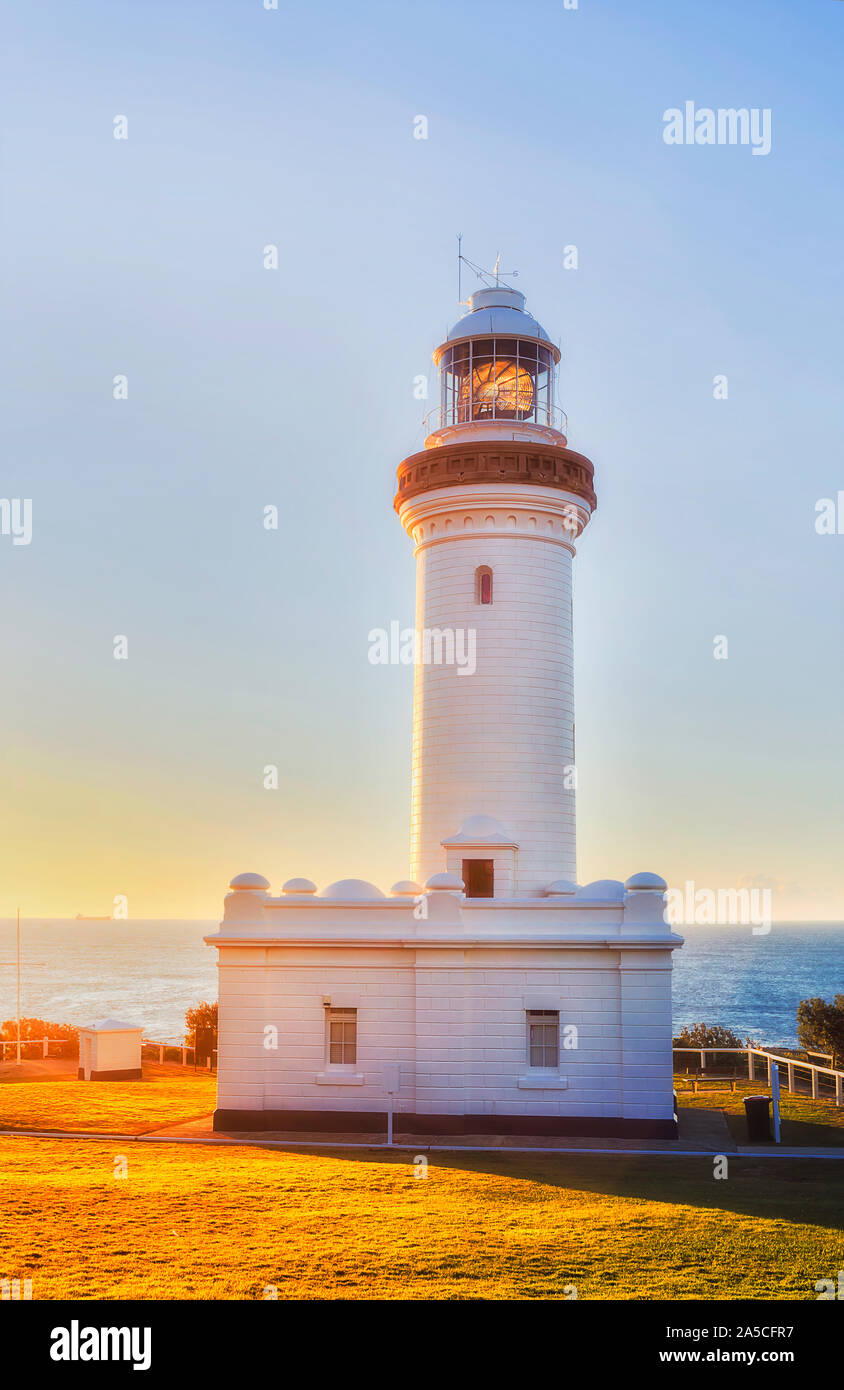 WHite stone Norah lighthouse in soft warm morning rising sun ligth with reflection lens agains Pacific ocean and blue sky. Stock Photo