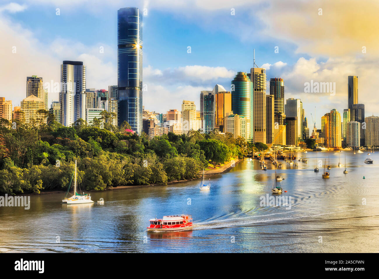Red ferry transporting passangers during morning communte across Brisbane river in Brisbane city in front of city CBD waterfront seen from elevation o Stock Photo