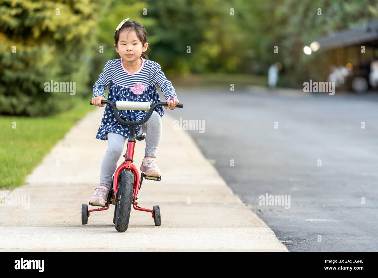 Cute little girl learning ride a bicycle with no helmet Stock Photo Alamy