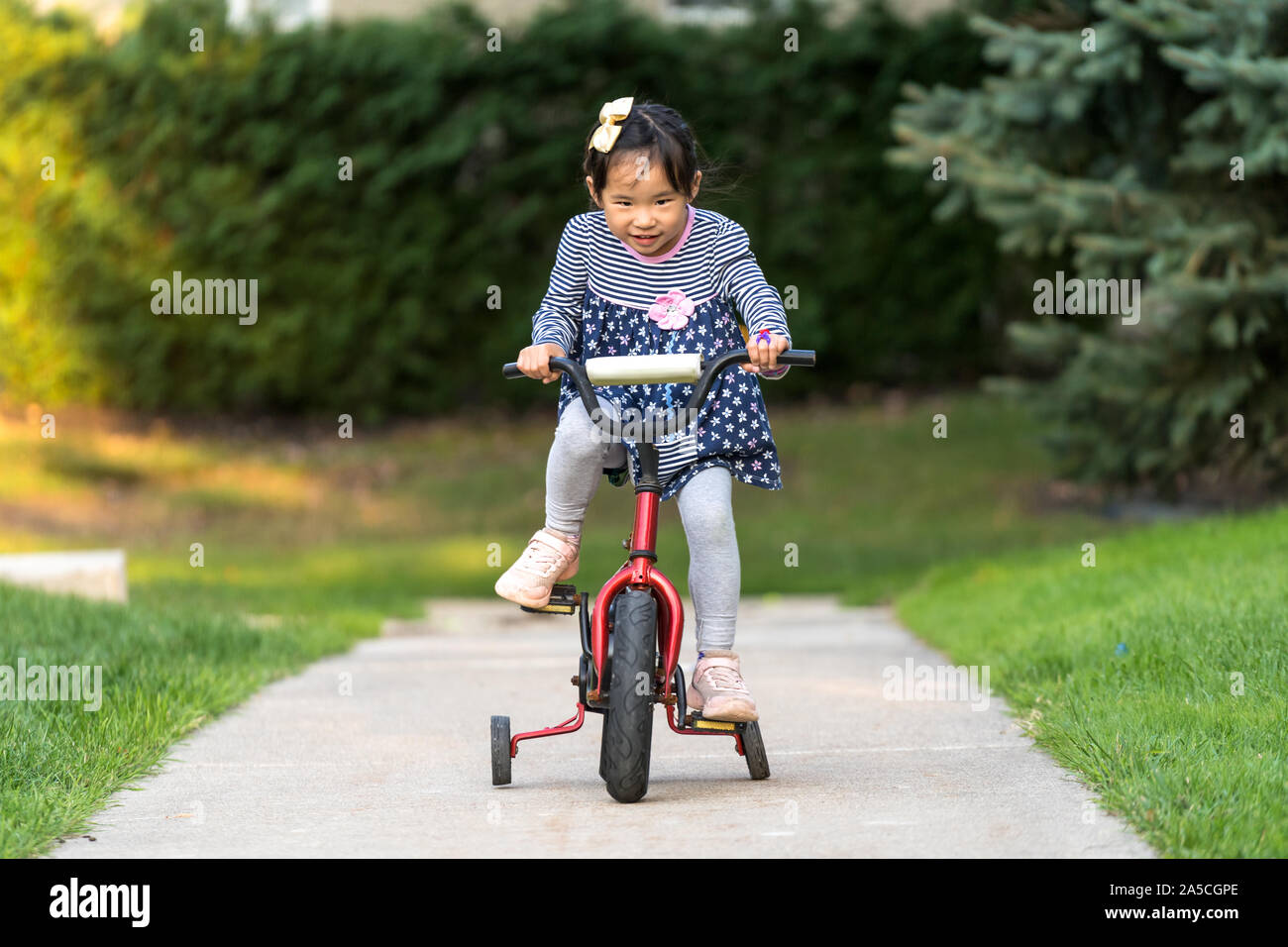 Cute little girl learning ride a bicycle with no helmet Stock Photo