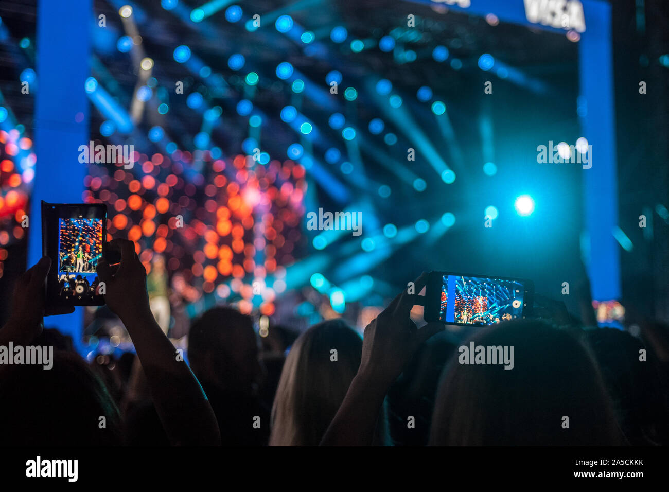 Shapes of people taking photos and videos with a smartphone telephone of a concert during a party, at night, with light and sound effects, typical fro Stock Photo