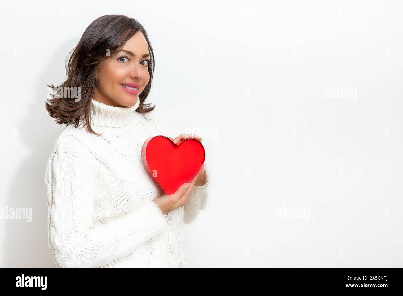 Happy beautiful woman holding a red heart on her hands isolated on ...