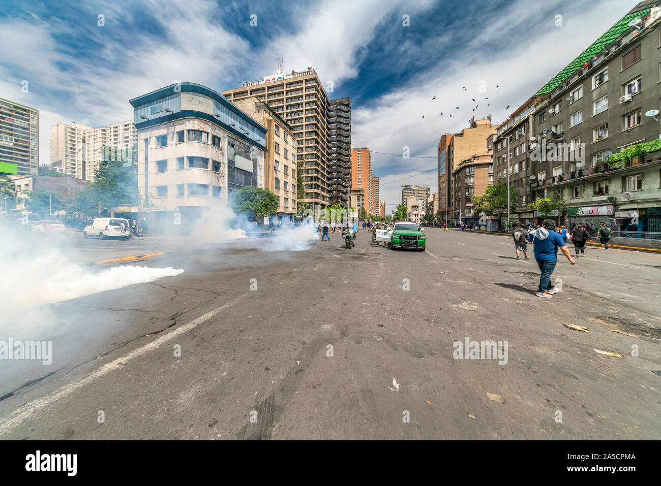 Police cars, officers, protesters and tear gas at Santiago streets during the riots at Santiago, Chile, city centre. 19/10/2019 Stock Photo