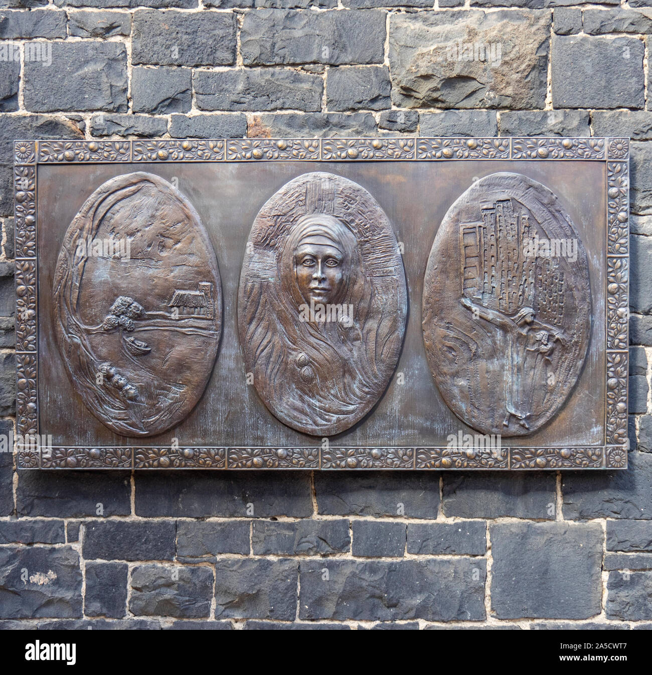 Bronze triptych plaque of life of Saint Mary MacKillop on a wall. Stock Photo