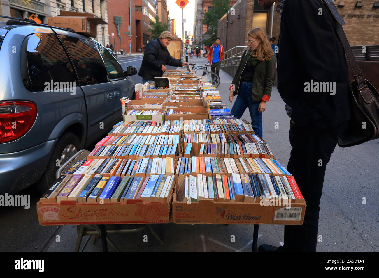 People browsing used books at a sidewalk bookseller in New York City