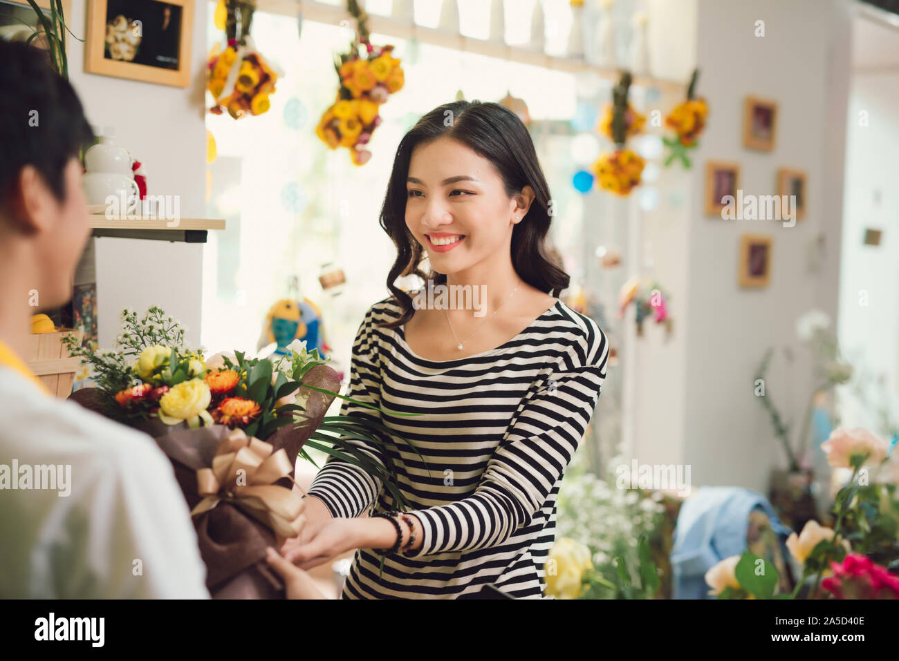 Florist giving bouquet of flower to woman in flower shop Stock Photo