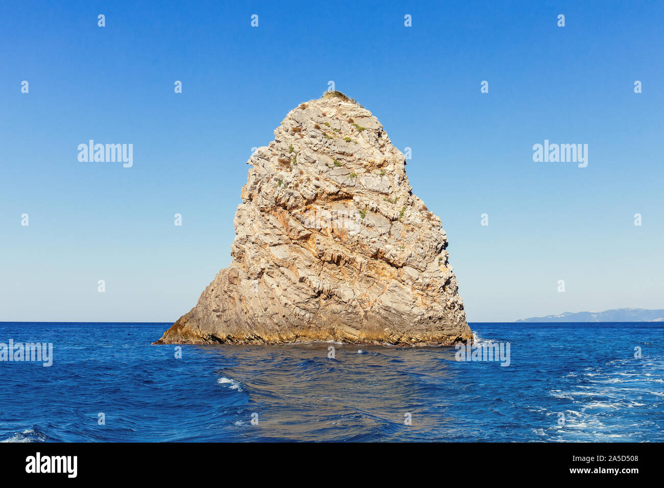 Single rock with clear blue sea water and reflection Stock Photo - Alamy