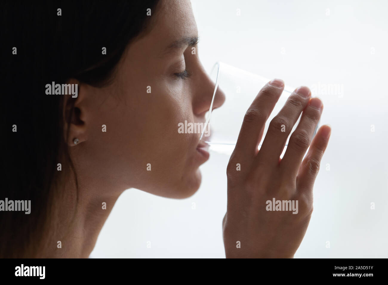 Millennial mixed race lady enjoying glass of pure filtered water. Stock Photo