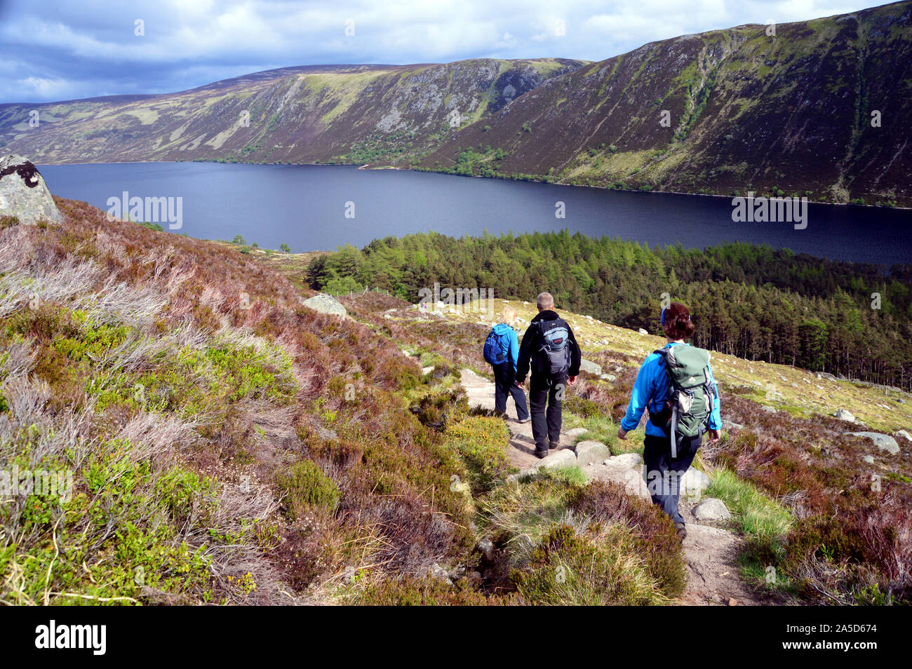 Three Hikers Walking to Loch Muick after Climbing the Scottish Mountain Munro Lochnagar, Glen Muick, Cairngorms National Park, Scotland.UK. Stock Photo