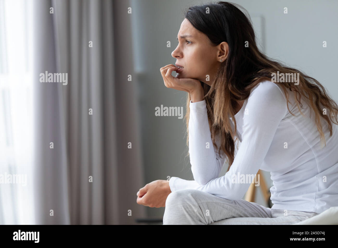 Confused anxious young mixed race woman biting nails. Stock Photo