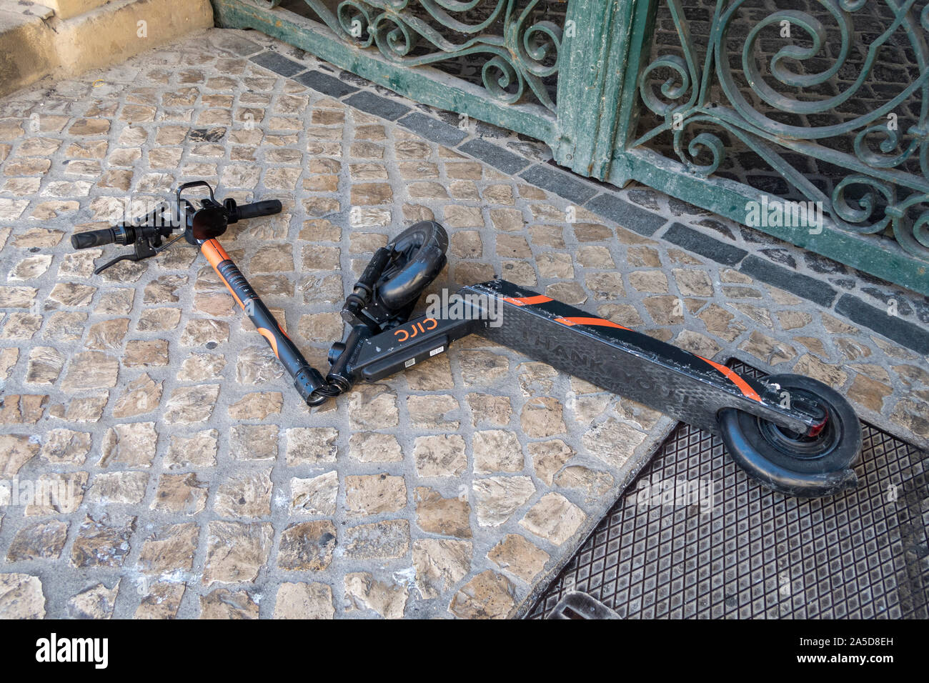 Vandalized electric e-scooter tossed on the sidewalk with broken steering column Stock Photo