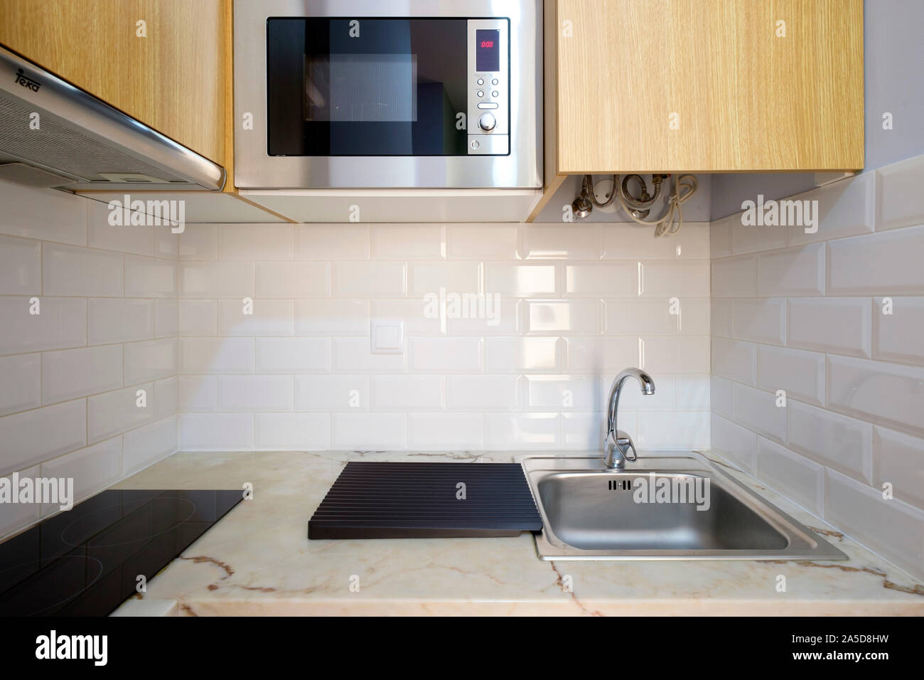 Tiny modern kitchen counter with microwave oven, sink and stove top Stock Photo