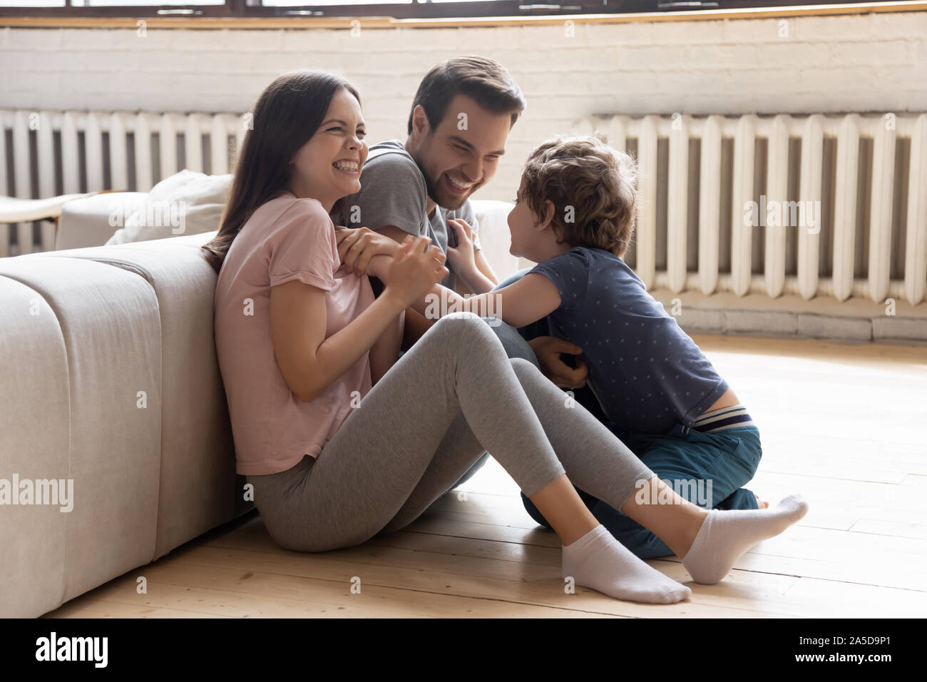 Happy mother and father playing with little son on floor Stock Photo