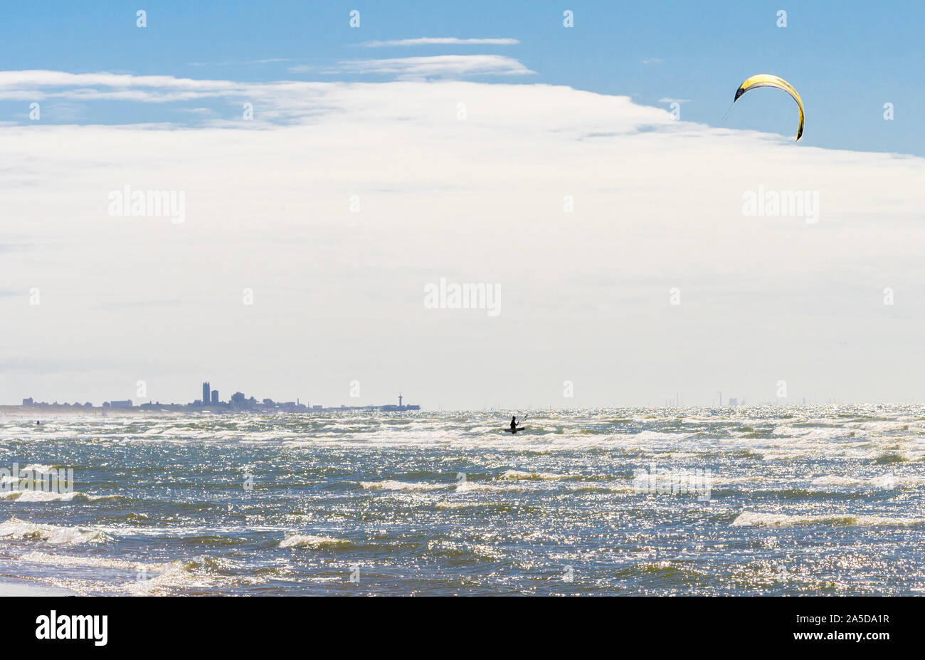 Passing in front of the city skyline of The Haag (Den Haag), a kite surfer is enjoying the stormy North Sea on a beach at Katwijk, Netherlands. Stock Photo