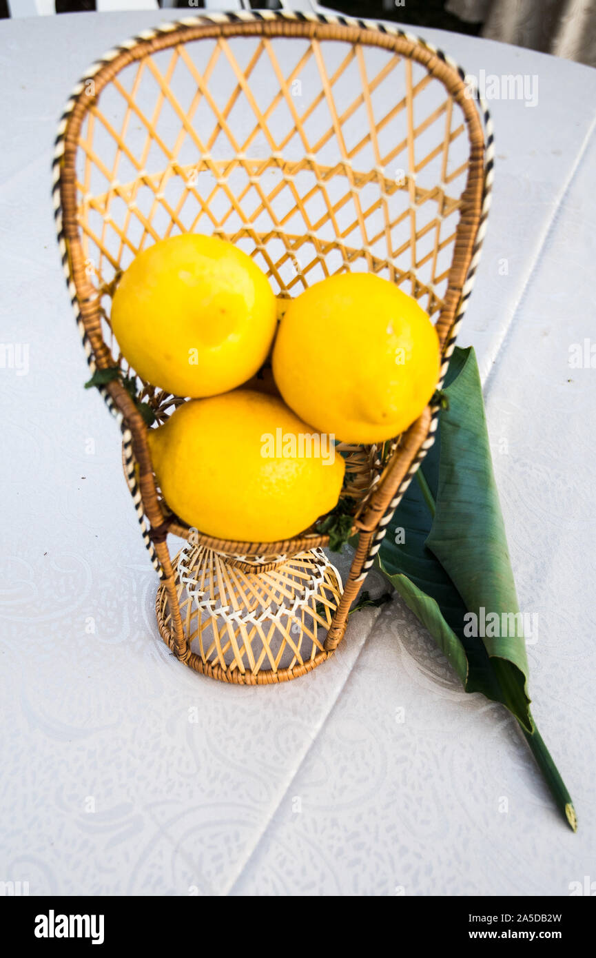 An outdoor table setting with a citrus decoration as a colorful decoration where a number of lemons are held in decorative containers. Stock Photo