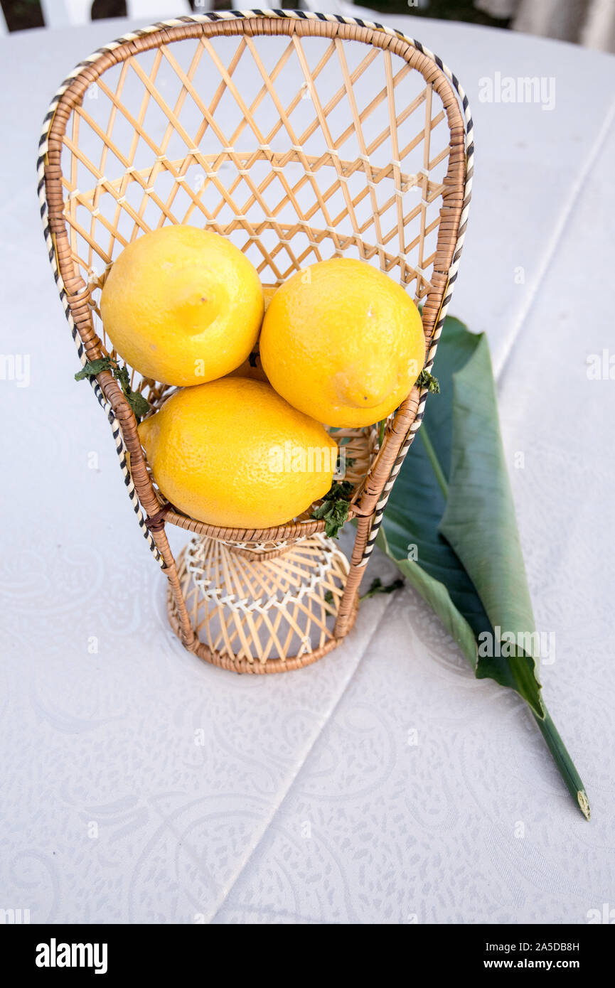 An outdoor table setting with a citrus decoration as a colorful decoration where a number of lemons are held in decorative containers. Stock Photo