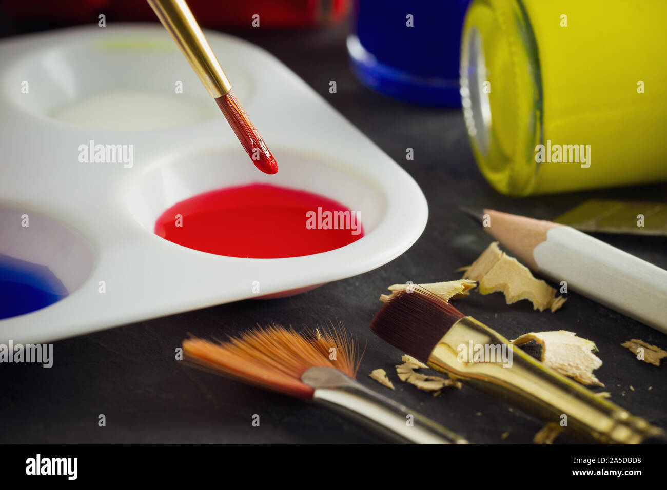 Paint palette on plate and glass containing brushes Stock Photo - Alamy