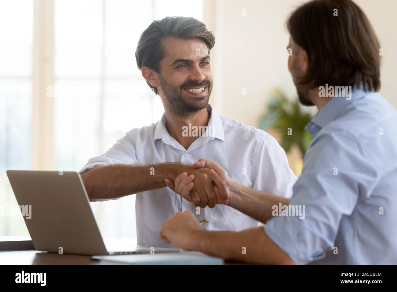 Happy businessman salesman manager handshake satisfied client at meeting Stock Photo