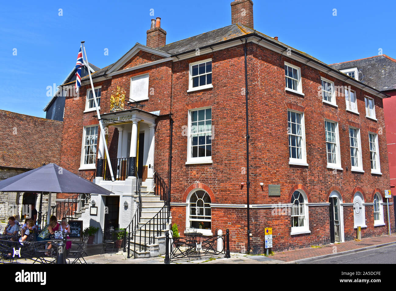 The Custom House Café on the quayside in Old Poole, with views across the harbour. People enjoying the summer sun sitting outside this historic house. Stock Photo