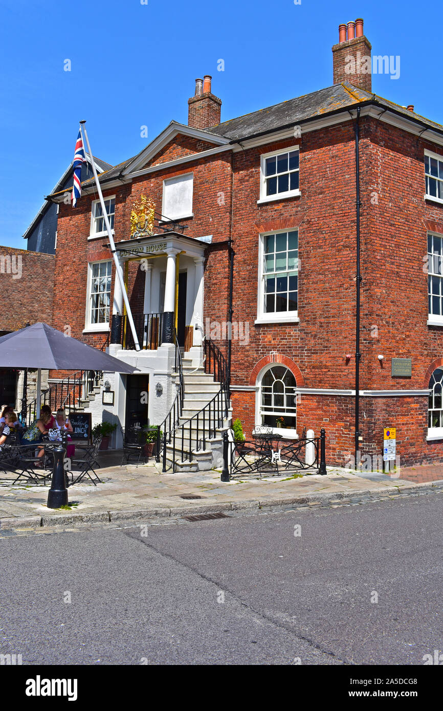 The Custom House Café on the quayside in Old Poole, with views across the harbour. People enjoying the summer sun sitting outside this historic house. Stock Photo