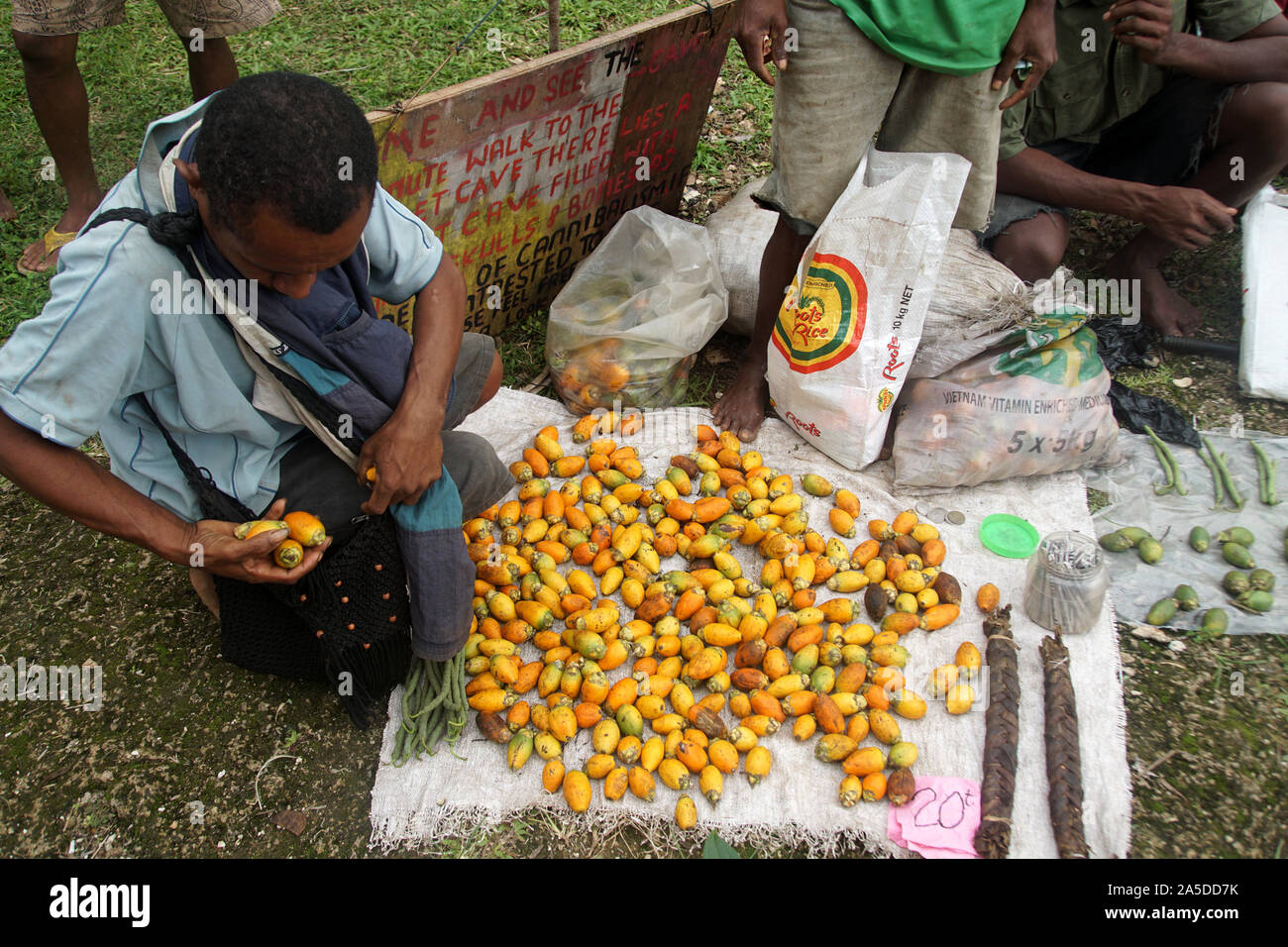 Man buying ripe orange Betel Nuts from a Market Stall on Kiriwina Island Stock Photo