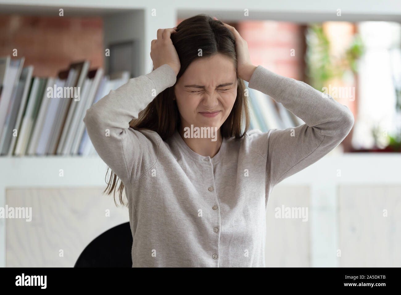 Stressed girl closed eyes touch head having terrible headache Stock