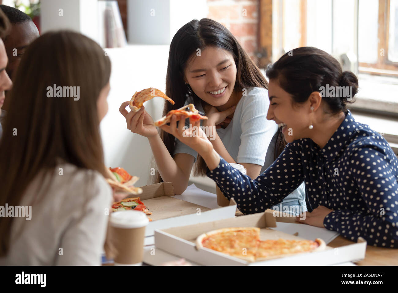 Multicultural students best friends gathered together eating pizza Stock Photo