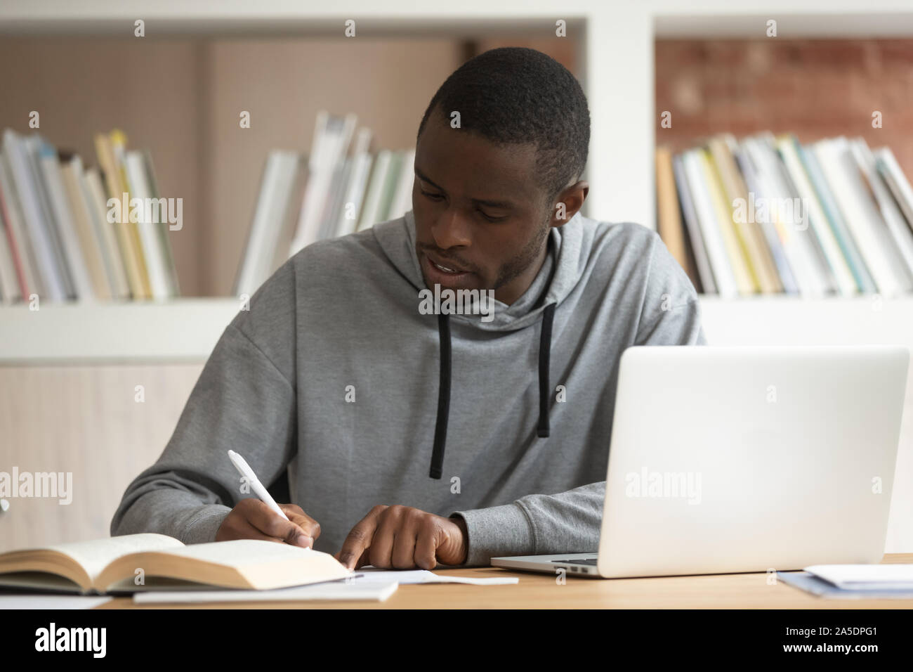 American fellow do schoolwork sitting at classroom table Stock Photo