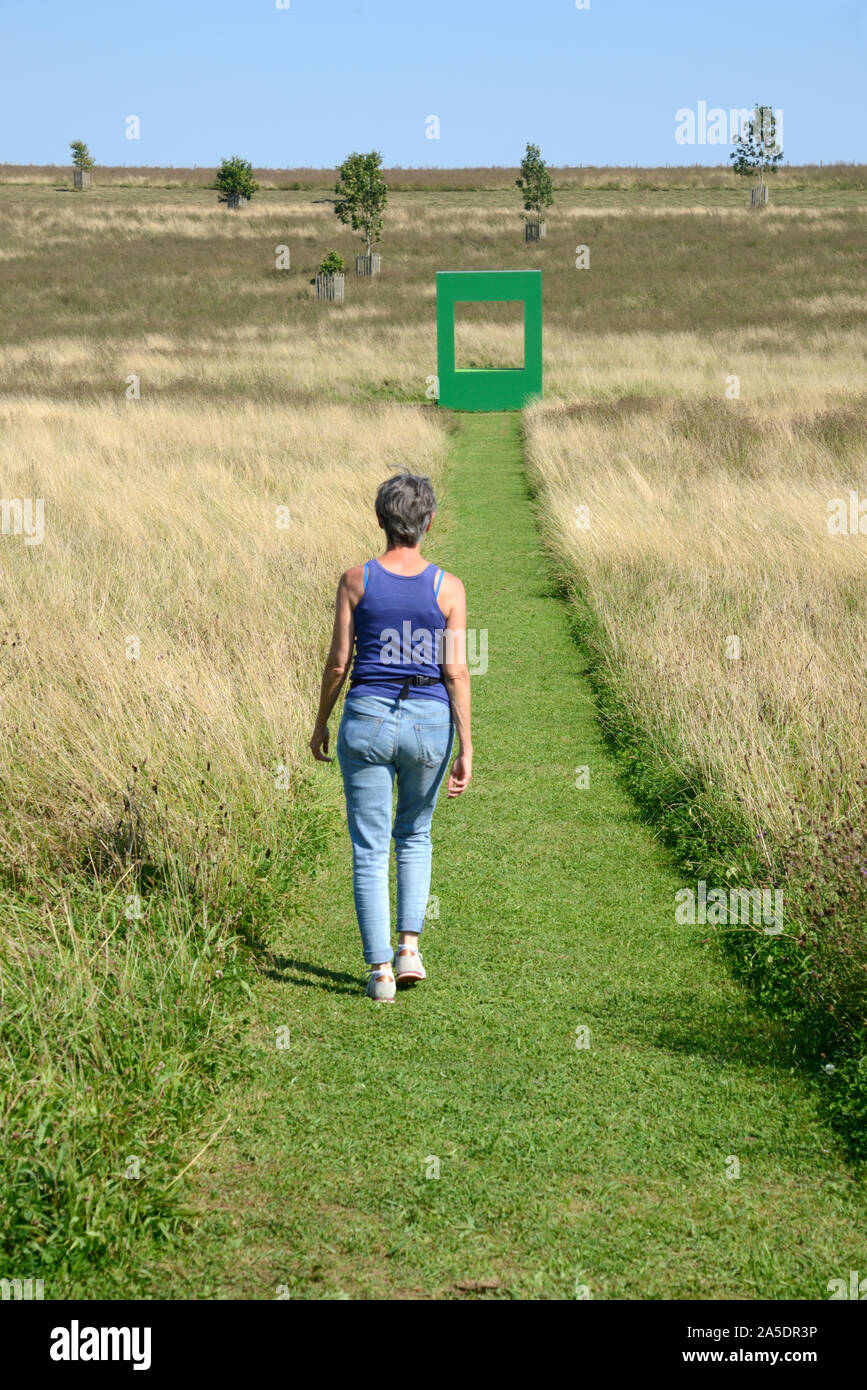 European Woman Walking Along Mown Grass in Field with Green Dwelling Art Installation by Krijn de Koning 2019 in Background Compton Verney England Stock Photo