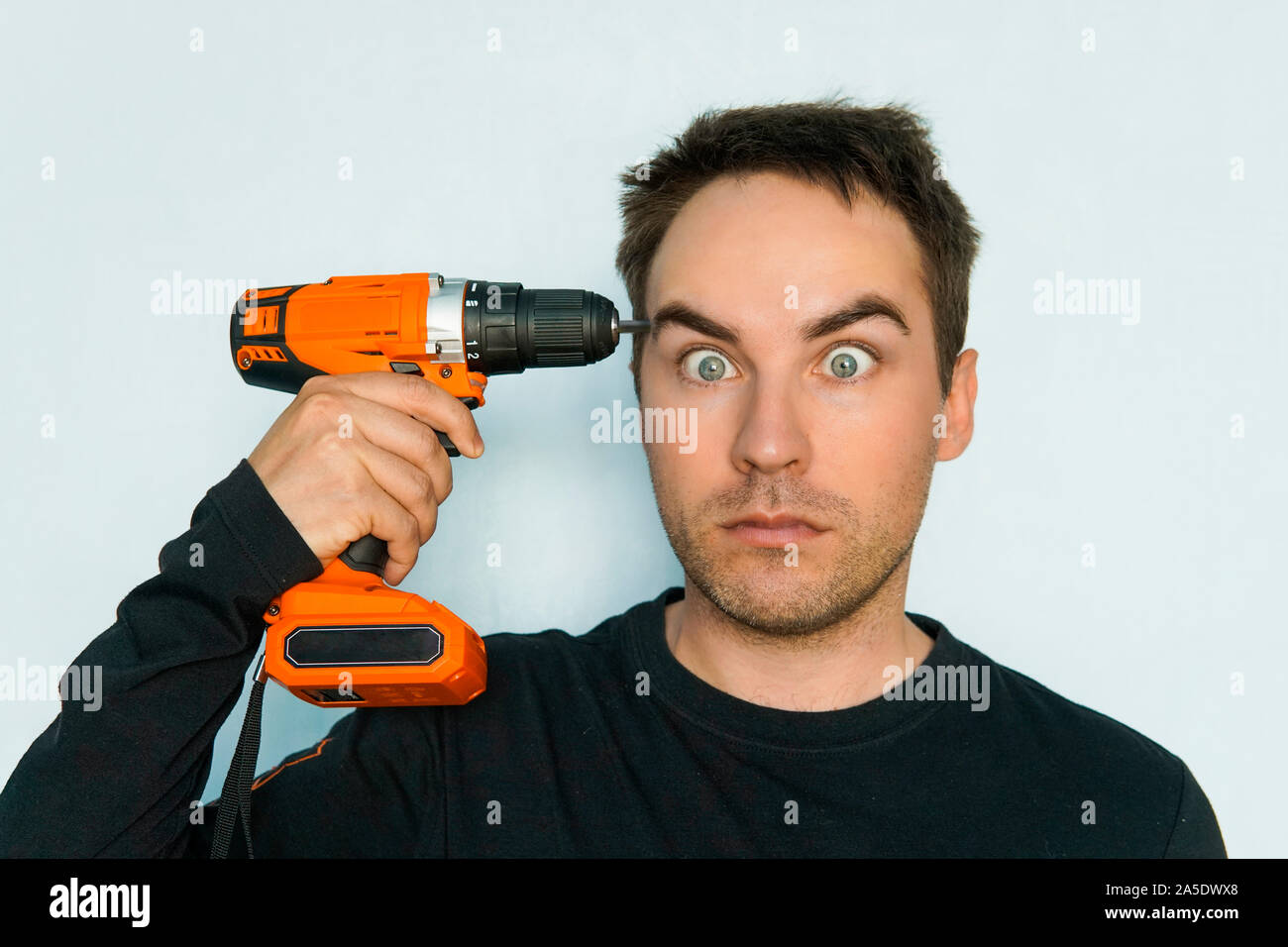 out of my mind. male Builder drills his brains out. Crazy guy with a stupid face. Fatigue from hard work. Inadequate customer. portrait of psychopath Stock Photo