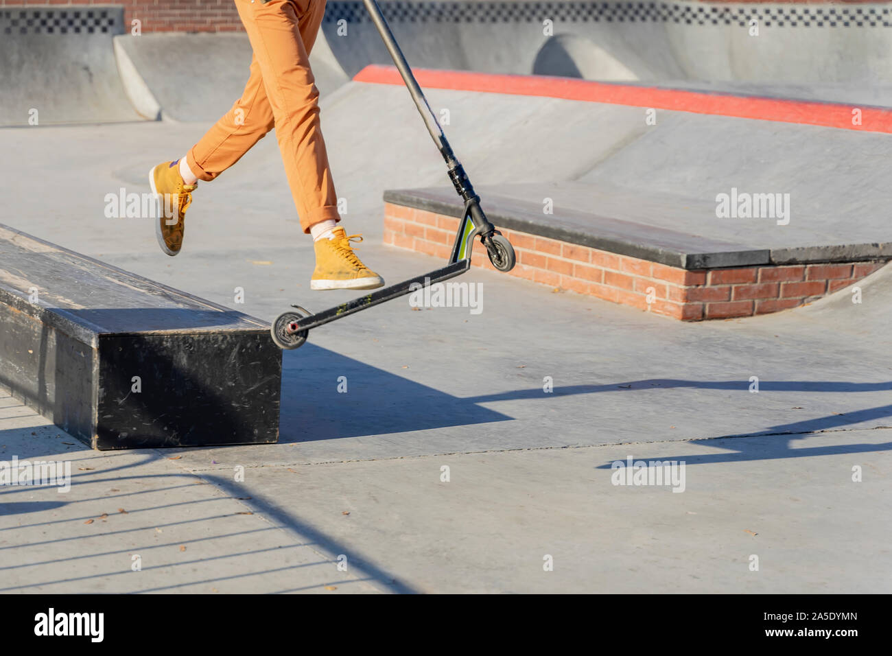 Feet in sneakers of teenager jumping a kick scooter at a skate park. Street culture of young Stock Photo