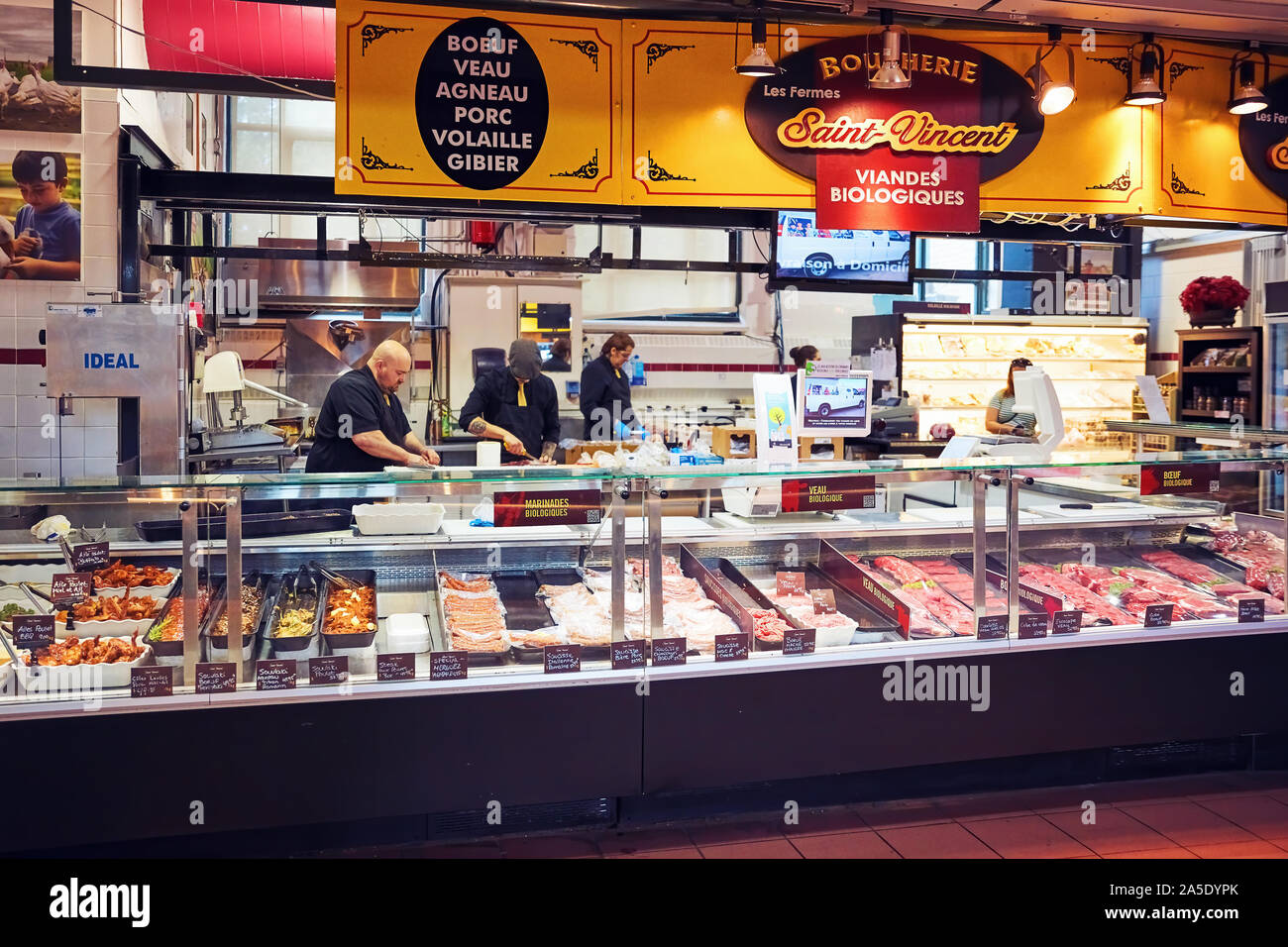 Canadian workers cutting and preparing meat behind the counter at Saint Vincent butchery shop at Atwater market in Montreal Stock Photo