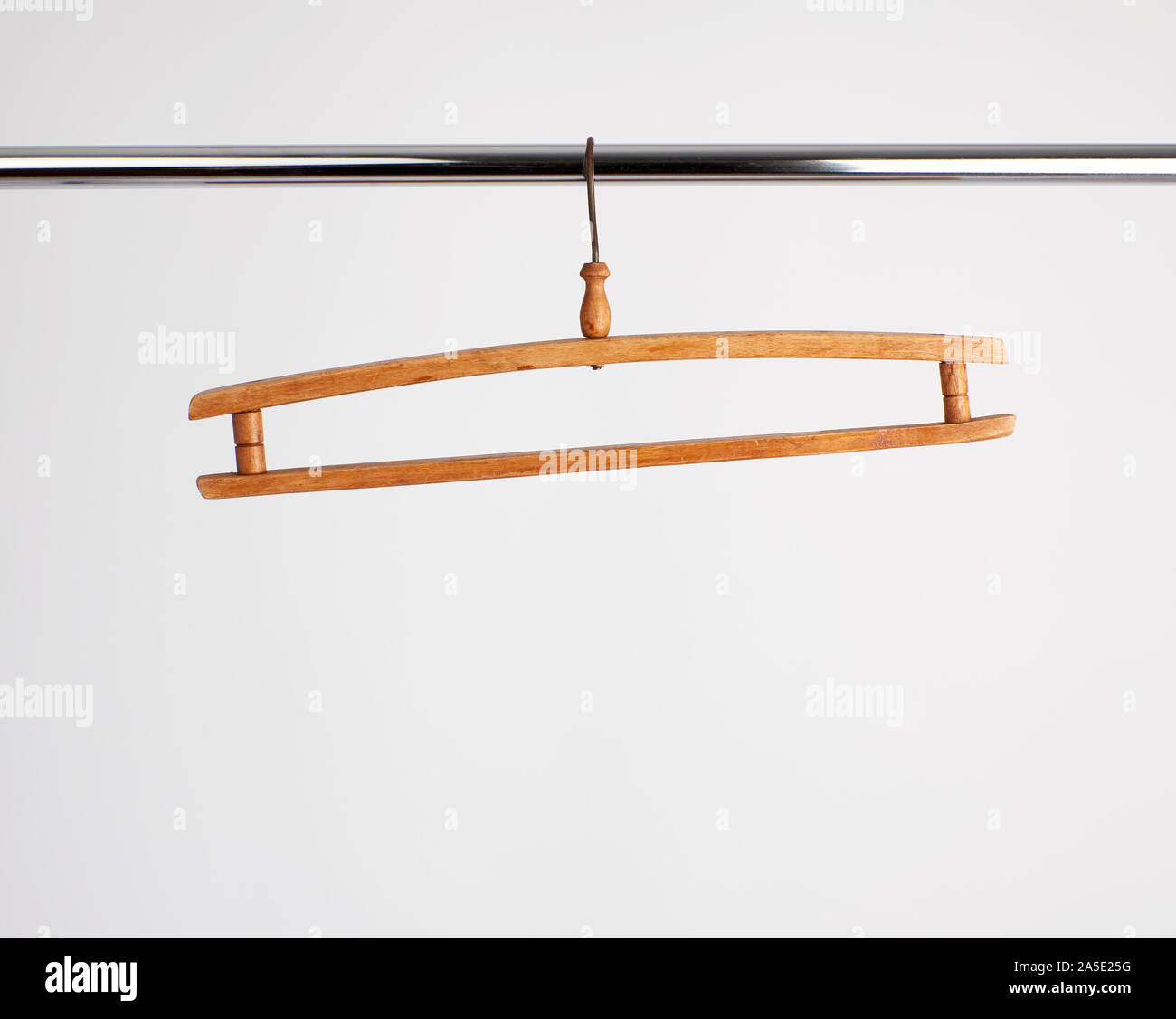 vintage wooden hanger hanging on a metal pipe, white background Stock Photo